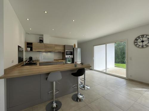 une cuisine avec un comptoir avec des tabourets et une horloge sur le mur dans l'établissement Menta, à Irouléguy