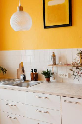 d'une cuisine avec un évier et un mur jaune. dans l'établissement Maison POP à la campagne, à Issy-lʼÉvêque