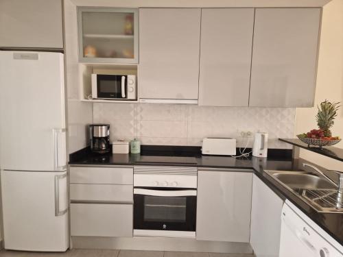 a kitchen with white cabinets and a white refrigerator at Casa La Buena Vida in San Juan de los Terreros