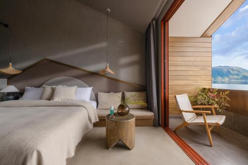 a bedroom with a bed and a chair and a window at QiPan Holiday hotel Lugu Lake in Ninglang