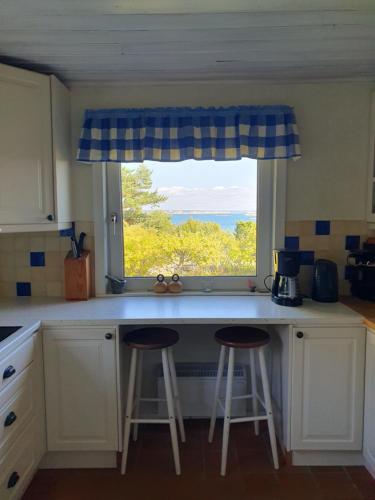 a kitchen with two bar stools in front of a window at Boende på SydKoster med havsutsikt och nära till bryggor in Strömstad