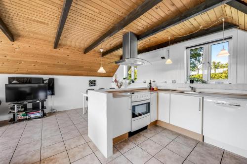 a kitchen with white cabinets and a wooden ceiling at Just 500 Meters From Both The Sea And The Town, This Lovely, Well-Maintained Holiday Home Is Situated in Ringkøbing