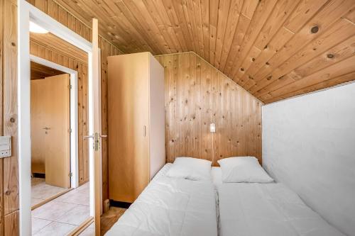 a bed in a room with a wooden ceiling at Just 500 Meters From Both The Sea And The Town, This Lovely, Well-Maintained Holiday Home Is Situated in Ringkøbing