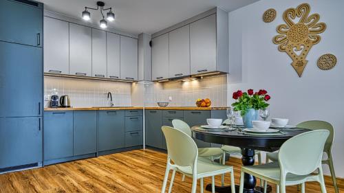 a kitchen with blue cabinets and a table with chairs at Źródło Izery przy gondoli VIP Sauna, Siłownia, Bawialnia by Royal Aparts in Świeradów-Zdrój