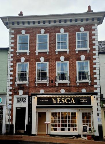 a large red brick building with a store at Esca with Rooms in Ross on Wye