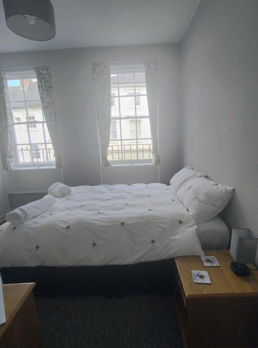a bedroom with a white bed and two windows at Esca with Rooms in Ross on Wye