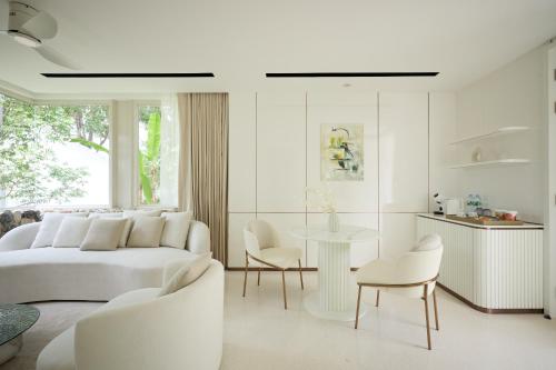 a white bedroom with a bed and a table and chairs at Mont Fleur Hotel in Ban Tha Chang