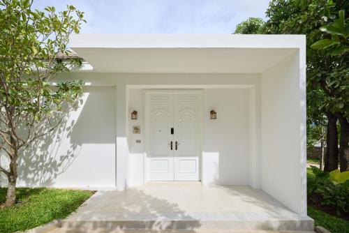 a white front door of a white house at Mont Fleur Hotel in Ban Tha Chang