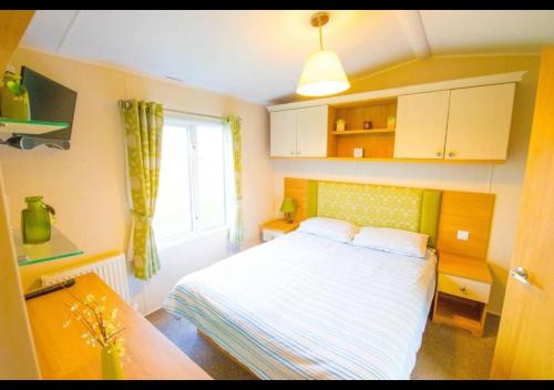 a small bedroom with a bed and a window at MP124 - Camber Sands Holiday Park - Sleeps 6 - Full Decking - Beautiful Marsh Views in Camber
