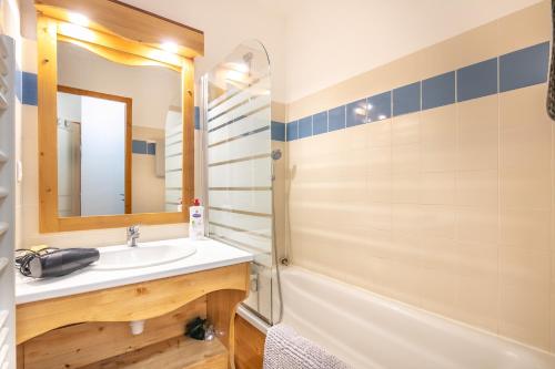 une salle de bain avec un lavabo, une baignoire et un miroir dans l'établissement Aventures à Chamrousse - Appt 34 m² avec terrasse, à Chamrousse