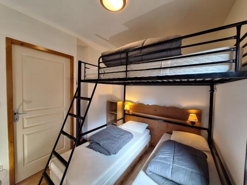 - 2 lits superposés dans une petite chambre avec une porte dans l'établissement Aventures à Chamrousse - Appt 34 m² avec terrasse, à Chamrousse