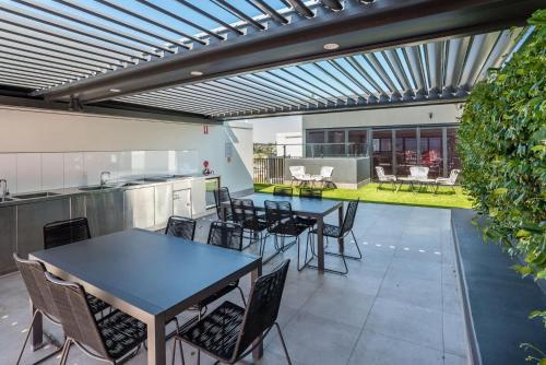 a patio with tables and chairs and a kitchen at Stones Corner Vista Stay in Brisbane