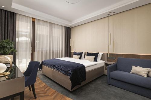 a bedroom with a bed and a blue chair at Avalon Resort & SPA in Miskolctapolca