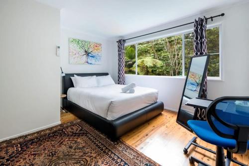 Un dormitorio con una cama y un escritorio y una ventana. en Hope Cottage Tamborine Mountain, en Mount Tamborine