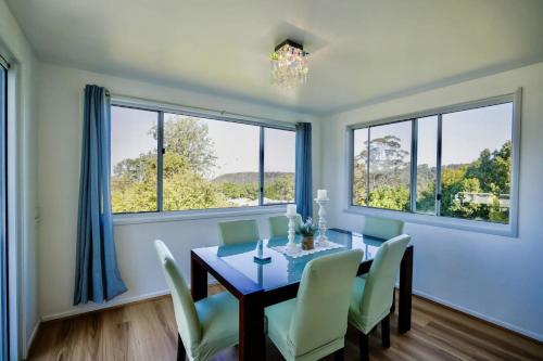a dining room with a table and chairs and windows at Family & Friends Escape Tamborine Mountain in Mount Tamborine