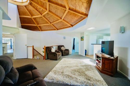 a living room with a couch and a flat screen tv at Family & Friends Escape Tamborine Mountain in Mount Tamborine