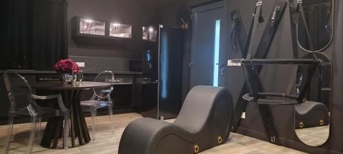 Zimmer mit einem Tisch, einem Stuhl und einem Tisch in der Unterkunft "BLACQ ROOM" Luxe, balnéo, sauna 50 nuances de grey in Boeschèpe