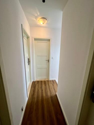 an empty hallway with a white door and wooden floors at Casa de Rainer Copenhagen Room 8 in Copenhagen