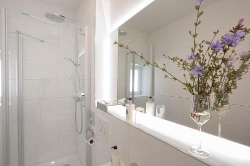 a bathroom with a shower and a vase with purple flowers at Hotel Kredell in Neckargemünd
