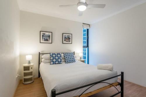Un dormitorio con una cama con almohadas azules y una ventana. en Stylish City Getaway with Pool Gym Parking, en Brisbane
