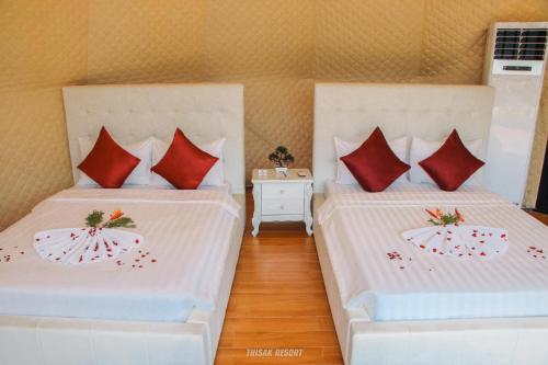 two beds with red pillows in a room at Thisak Resort Cheung phnom kulen in Siem Reap