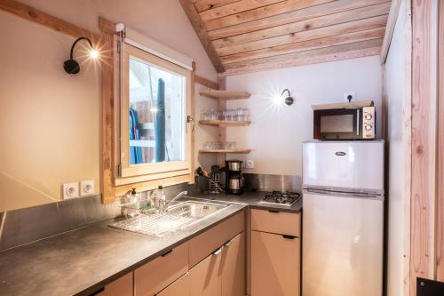 La cuisine est équipée d'un réfrigérateur et d'un évier. dans l'établissement Huttopia Bozel en Vanoise, à Bozel