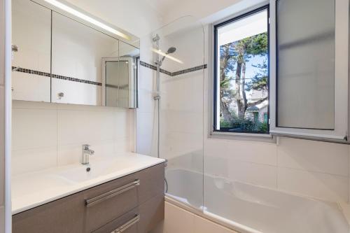 une salle de bain avec un lavabo, un miroir et une fenêtre dans l'établissement Cosy T2 Mer & Détente à vos pieds LA BAULE !, à La Baule
