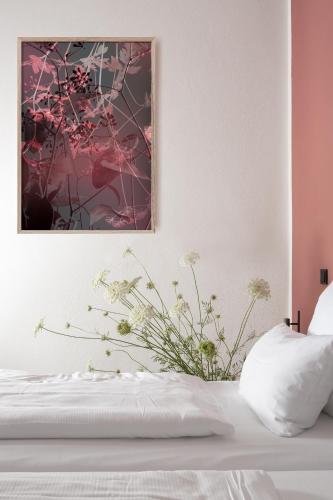 a bedroom with a white bed with a painting on the wall at Hotel Kredell in Neckargemünd