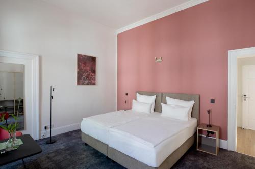 a bedroom with a white bed and a pink wall at Hotel Kredell in Neckargemünd