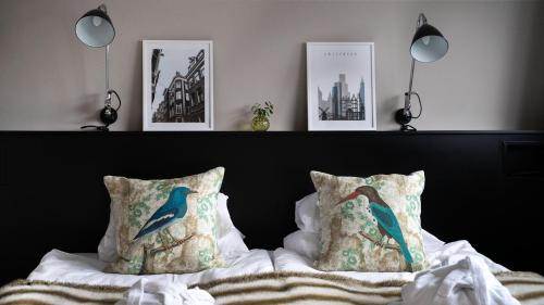 a bed with two pillows on it with pictures on the wall at Sigtunahöjden Hotell & Konferens in Sigtuna