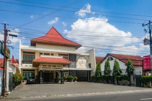 a building with a red roof on a street at RedDoorz near XT Square Yogyakarta in Yogyakarta