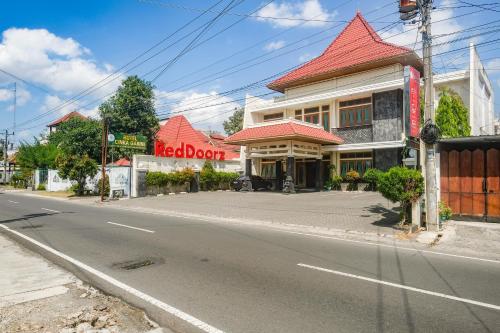 a building with a red roof on the side of a street at RedDoorz near XT Square Yogyakarta in Yogyakarta