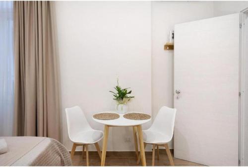 a table with white chairs and a vase on it at Pompei Luxury Suite in Pompei