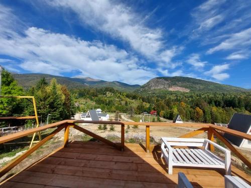 a wooden deck with a bench and mountains at Valea Lui Neag in Cîmpu lui Neag
