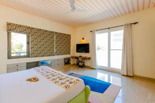 a bedroom with a bed and a tv and a window at Karma Lakelands Golf Resort & Residences in Gurgaon