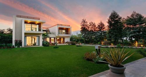 a house with a green yard with a rainbow in the sky at Karma Lakelands Golf Resort & Residences in Gurgaon
