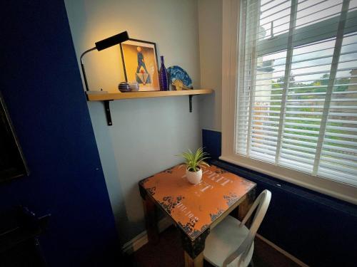 a table with a potted plant on it next to a window at Stylish and artistic flat in Southend on Sea in Southend-on-Sea