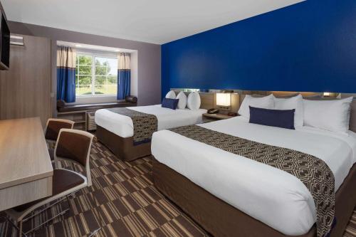 a hotel room with two beds and a blue wall at Microtel Inn & Suites by Wyndham Bethel/Danbury in Bethel
