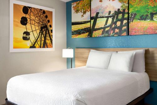 a bedroom with a bed and paintings on the wall at Days Inn by Wyndham Hershey in Hershey