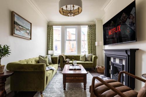 a living room with green furniture and a fireplace at Emerald Park - HOT TUB & GAMES ROOM! in Scarborough