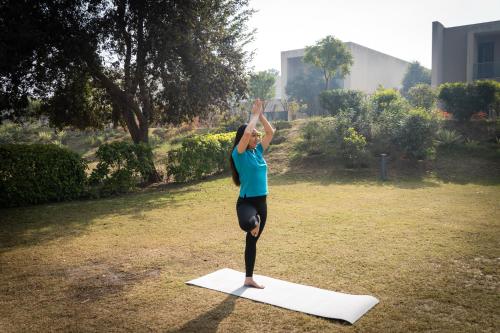 a woman doing a yoga pose on a yoga mat at Karma Lakelands Golf Resort & Residences in Gurgaon