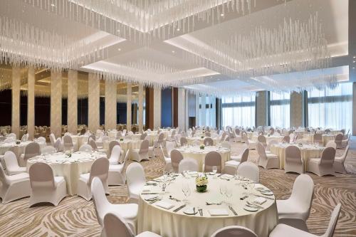 a banquet hall with white tables and chairs and chandeliers at Embassy Suites By Hilton Dubai Business Bay in Dubai