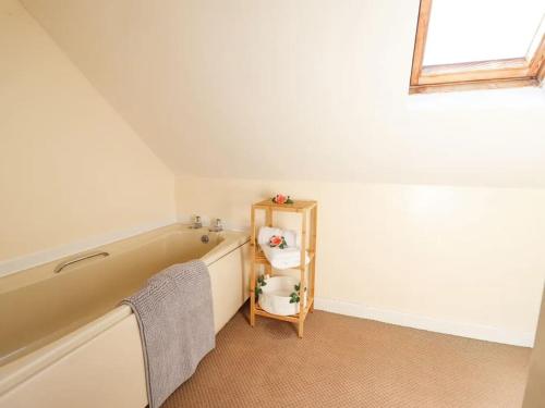 a bathroom with a tub and a shelf with towels at Bryn Glasfor in Barmouth