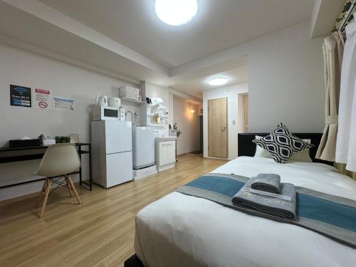 a bedroom with a bed and a kitchen with a refrigerator at nestay apartment tokyo kagurazaka in Tokyo
