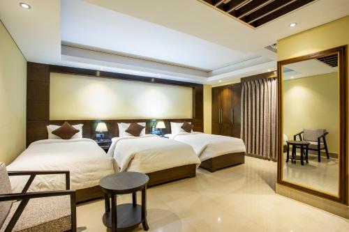 a hotel room with two beds and a mirror at Hotel Capital Xpress in Dhaka