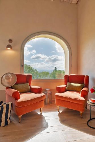 a living room with two chairs and a large window at Villa Mami - Boutique Suites Adults Only in Siena