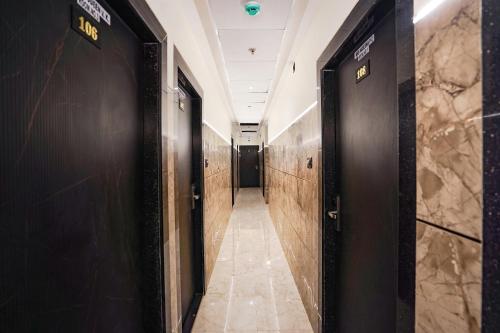 a corridor in a building with black doors and marble floors at FabHotel Well Back - Nr BKC in Mumbai