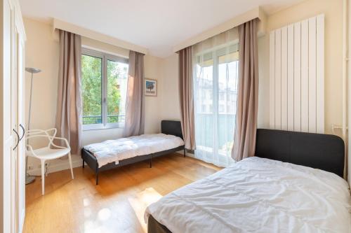 une chambre avec un lit, une chaise et des fenêtres dans l'établissement Spacious 3BD Family Apartment Auteuil, à Paris