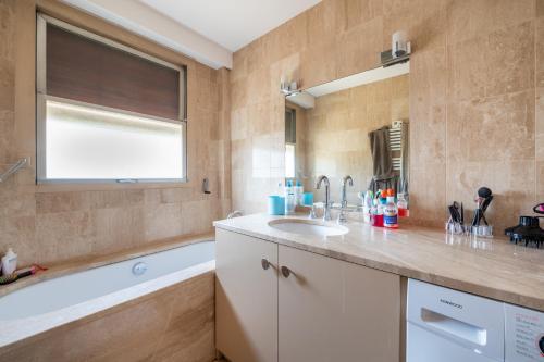 une salle de bain avec un lavabo et une baignoire dans l'établissement Spacious 3BD Family Apartment Auteuil, à Paris