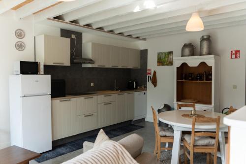 a kitchen with white cabinets and a table and a table and chairs at Kom à 2 in Vielsalm